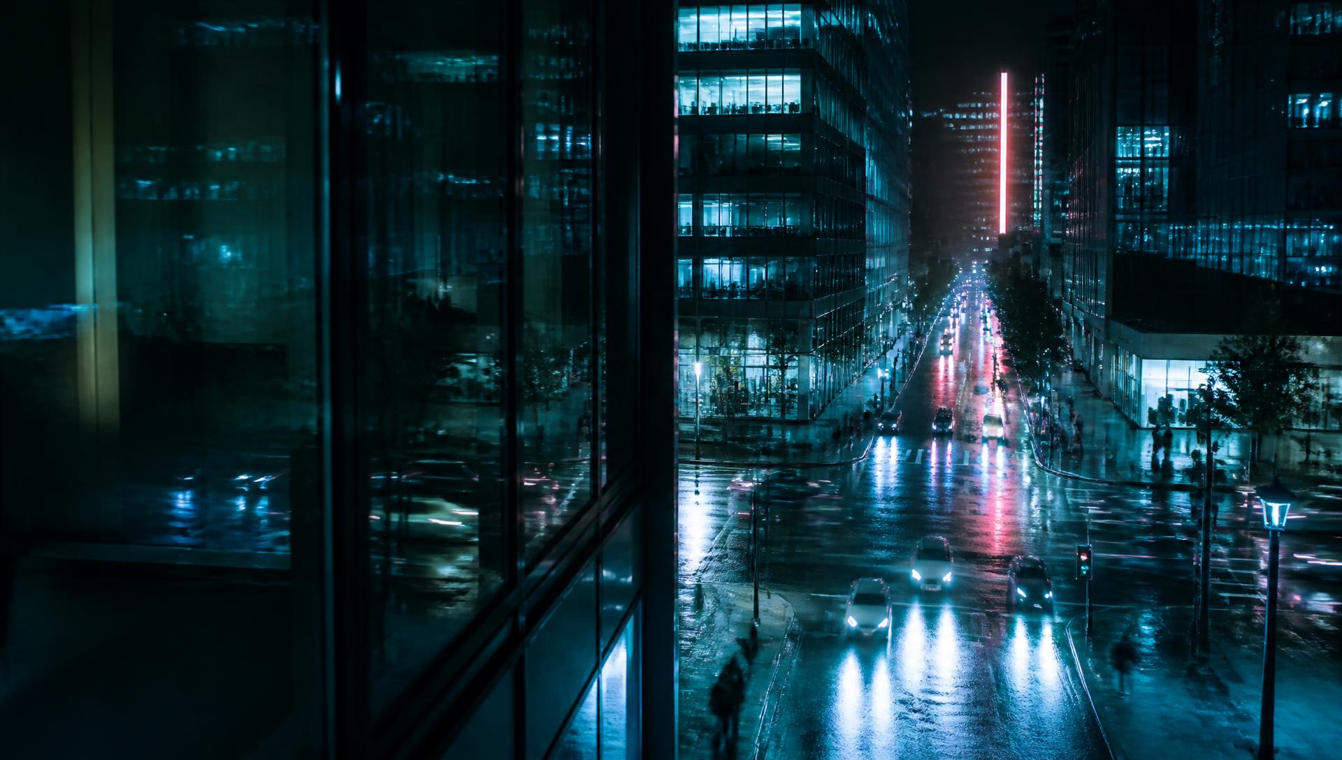 Rain-wet night city street reflecting cyan light and one pink sign